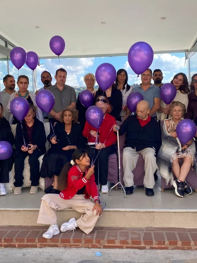 Bewohner und Team von GAYA Huzurevi gemeinsam bei einer Alzheimer-Aufklärungsveranstaltung mit lila Luftballons